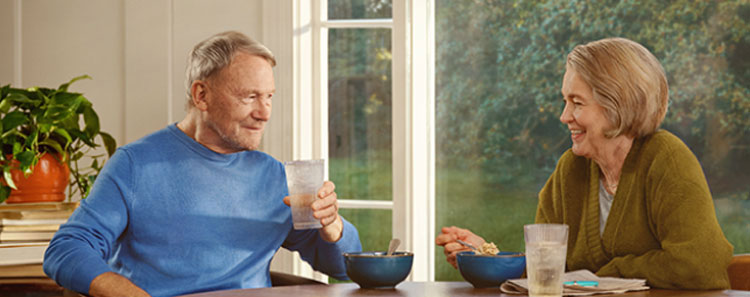 A couple laughing together while sitting at a table eating lunch. Actor portrayal